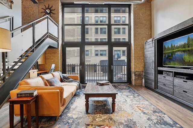 living room with a towering ceiling, brick wall, and wood-type flooring