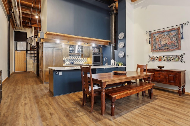 dining area featuring sink, light hardwood / wood-style floors, and a towering ceiling