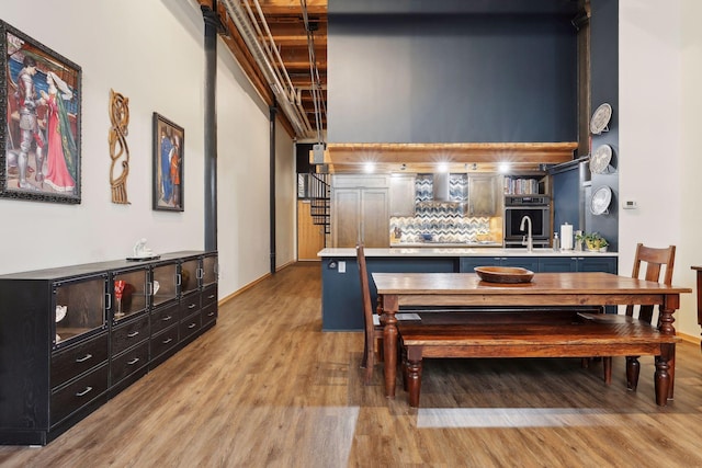 dining area with a towering ceiling, sink, and light wood-type flooring