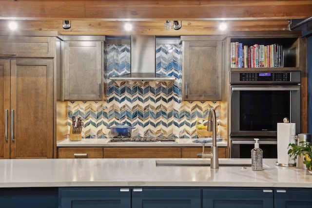 kitchen featuring wall chimney range hood, backsplash, and appliances with stainless steel finishes