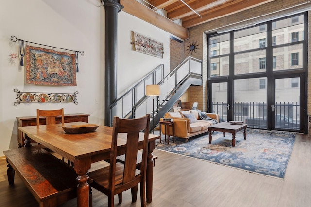 dining room with a high ceiling, decorative columns, dark hardwood / wood-style flooring, and beamed ceiling