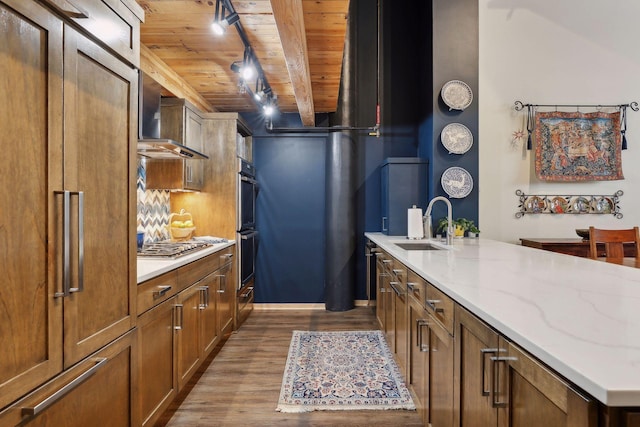 kitchen featuring wall chimney range hood, beamed ceiling, wood-type flooring, sink, and wooden ceiling