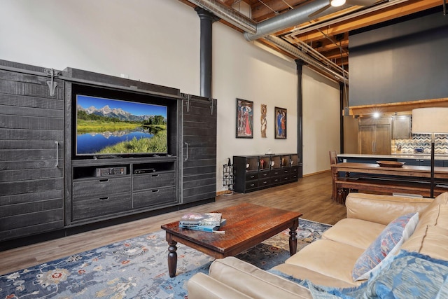 living room featuring a barn door, dark wood-type flooring, and a towering ceiling