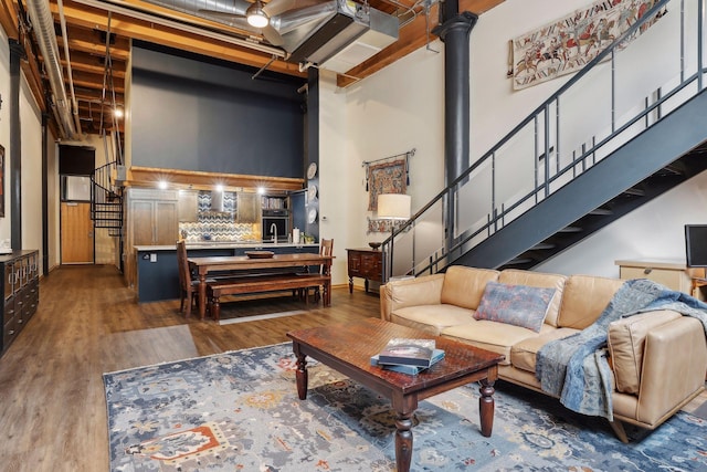 living room featuring dark hardwood / wood-style floors, ornate columns, and a towering ceiling