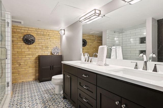 bathroom with walk in shower, tile floors, brick wall, toilet, and dual bowl vanity