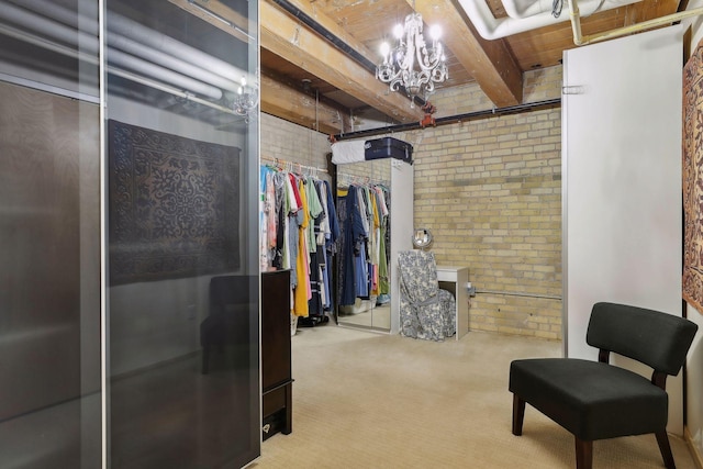 spacious closet with a notable chandelier, light carpet, and beamed ceiling