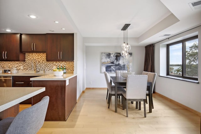 kitchen featuring sink, decorative backsplash, hanging light fixtures, and light hardwood / wood-style floors