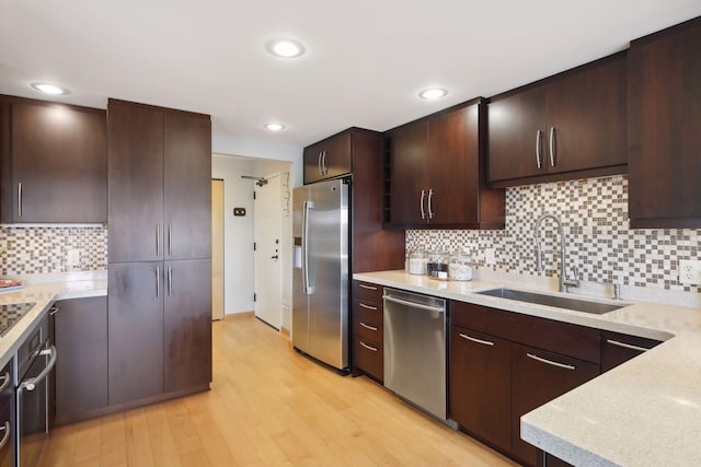 kitchen featuring appliances with stainless steel finishes, tasteful backsplash, sink, and light hardwood / wood-style floors