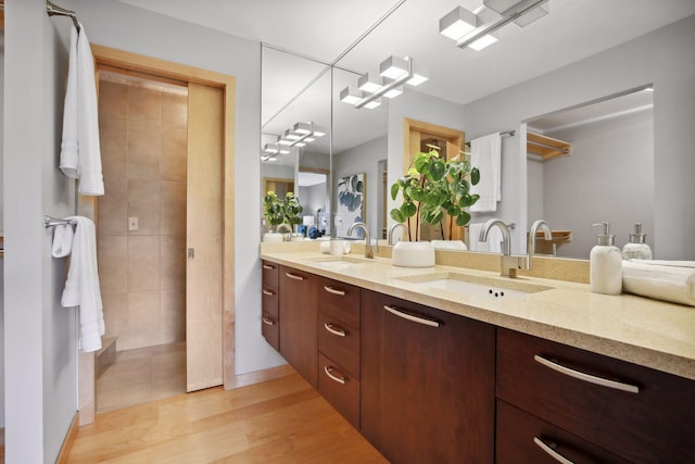 bathroom featuring vanity, wood-type flooring, and tiled shower