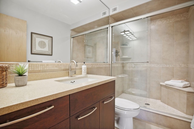 bathroom with a shower with door, vanity, and toilet