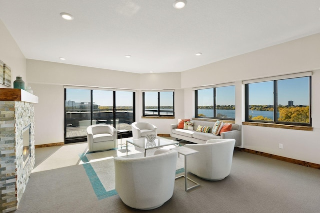 living room featuring a water view, a stone fireplace, and light colored carpet