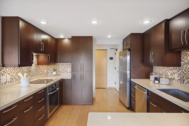 kitchen featuring tasteful backsplash, sink, light wood-type flooring, dark brown cabinets, and stainless steel appliances