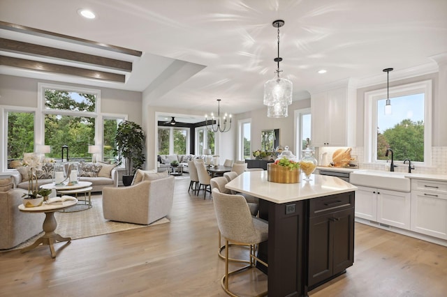 kitchen with tasteful backsplash, white cabinets, a notable chandelier, light hardwood / wood-style flooring, and sink