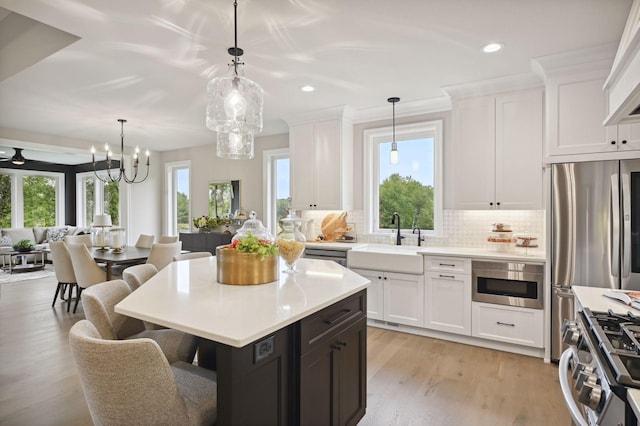 kitchen featuring light wood-type flooring, tasteful backsplash, sink, a healthy amount of sunlight, and white cabinets