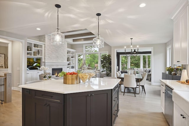 kitchen with pendant lighting, light hardwood / wood-style floors, a notable chandelier, and a fireplace