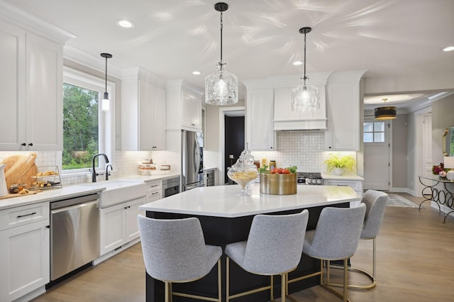 kitchen featuring backsplash, stainless steel appliances, white cabinetry, and light wood-type flooring