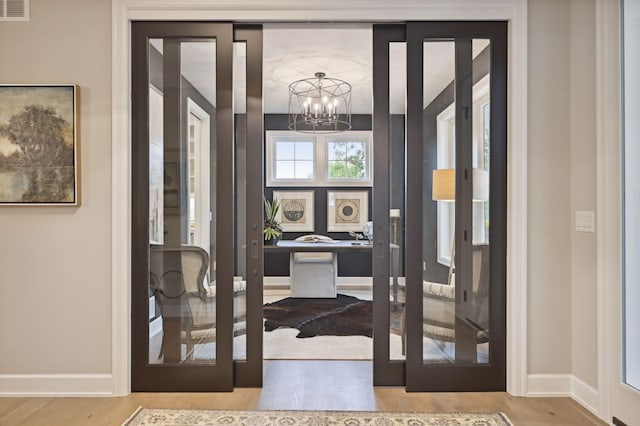 doorway featuring a notable chandelier and light hardwood / wood-style floors