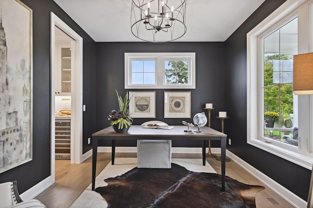 office with light wood-type flooring, a chandelier, and a healthy amount of sunlight