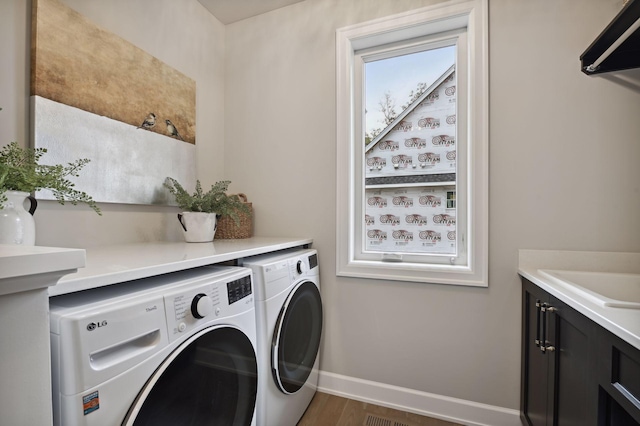 clothes washing area featuring independent washer and dryer, sink, cabinets, and dark hardwood / wood-style floors