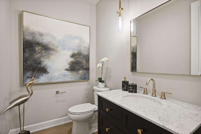 bathroom with toilet, vanity with extensive cabinet space, and hardwood / wood-style floors