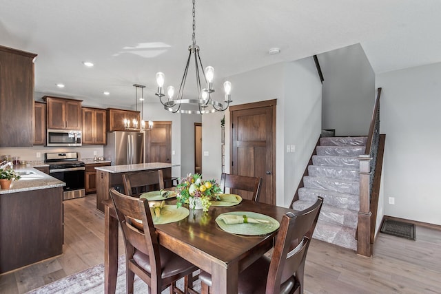 dining space featuring a notable chandelier, light hardwood / wood-style flooring, and sink