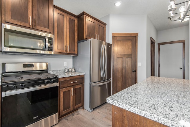 kitchen featuring appliances with stainless steel finishes, light hardwood / wood-style flooring, and an inviting chandelier