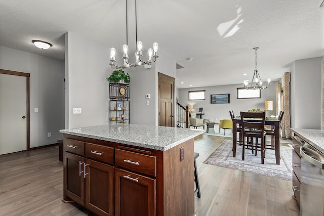 kitchen with a chandelier, light hardwood / wood-style floors, a breakfast bar area, a center island, and hanging light fixtures