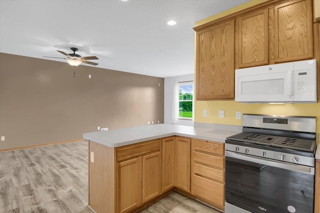 kitchen with light wood-type flooring, ceiling fan, gas stove, and kitchen peninsula