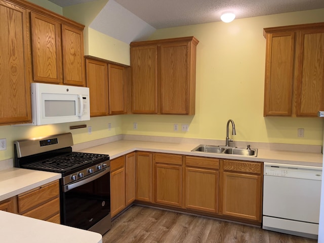 kitchen featuring a textured ceiling, dark wood-type flooring, sink, and white appliances