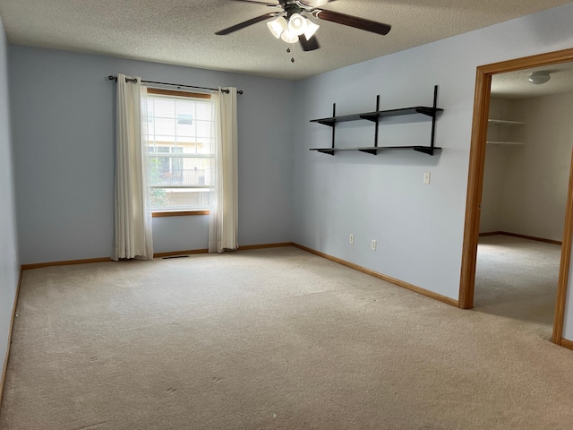 unfurnished room with a textured ceiling, ceiling fan, and light colored carpet