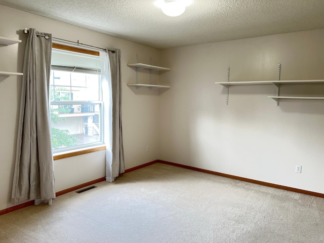 carpeted empty room featuring a textured ceiling