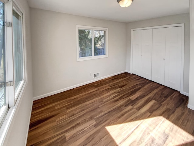 unfurnished bedroom with dark hardwood / wood-style flooring and a closet