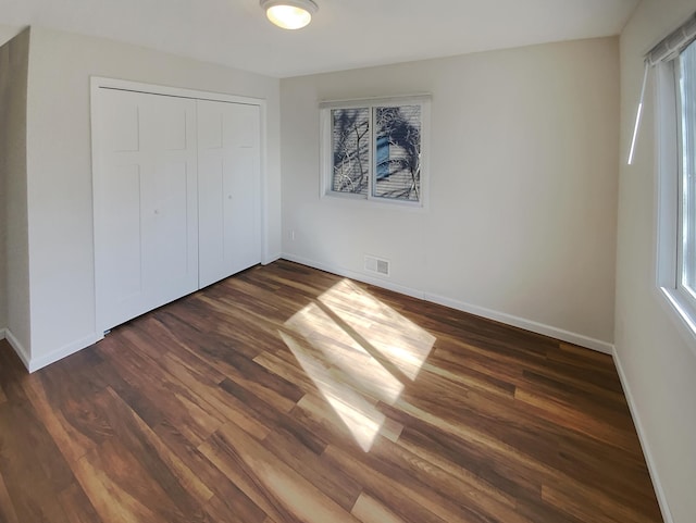 unfurnished bedroom featuring a closet and dark wood-type flooring