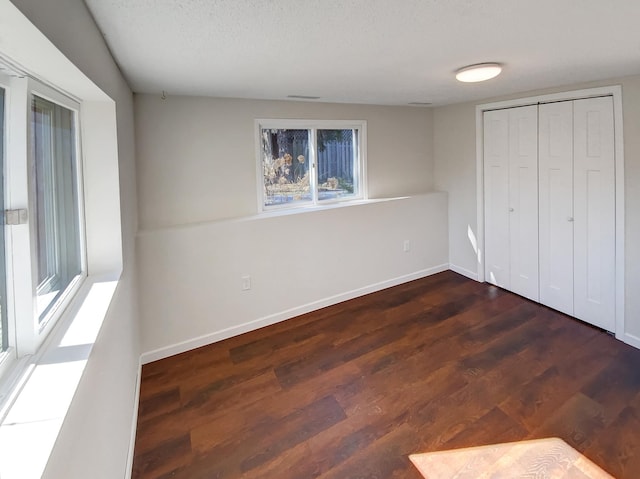 unfurnished bedroom featuring a textured ceiling, a closet, and dark hardwood / wood-style floors