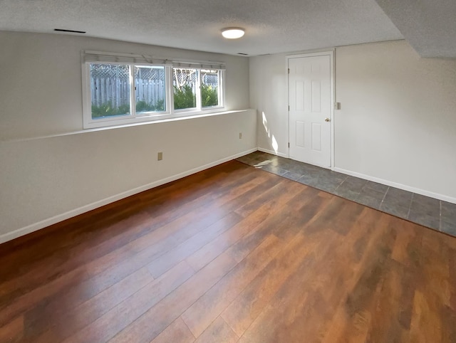 spare room with dark hardwood / wood-style floors and a textured ceiling