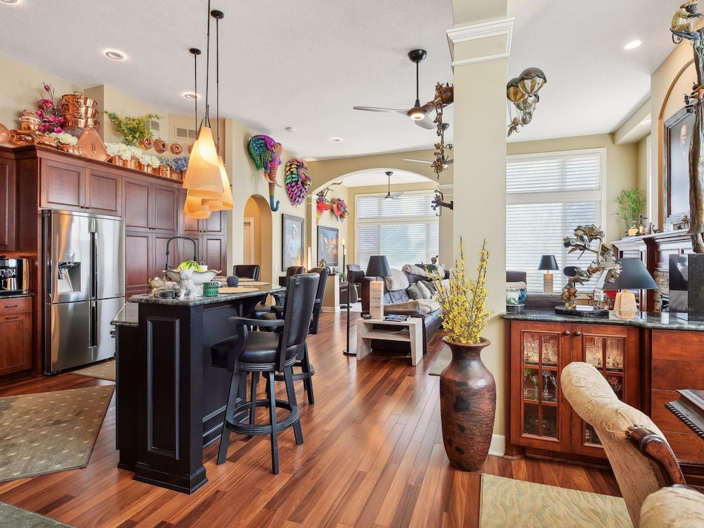 8807 Lake Riley Dr, Chanhassen, MN 55317 - kitchen with stainless steel refrigerator with ice dispenser, decorative light fixtures, dark stone countertops, dark hardwood / wood-style floors, and a kitchen breakfast bar