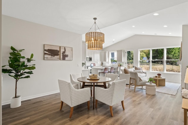 dining space with light hardwood / wood-style flooring, a chandelier, and lofted ceiling