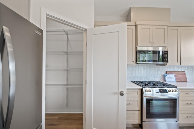 kitchen featuring appliances with stainless steel finishes, backsplash, and dark wood-type flooring