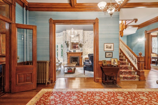 interior space with an inviting chandelier, crown molding, hardwood / wood-style flooring, beamed ceiling, and radiator heating unit