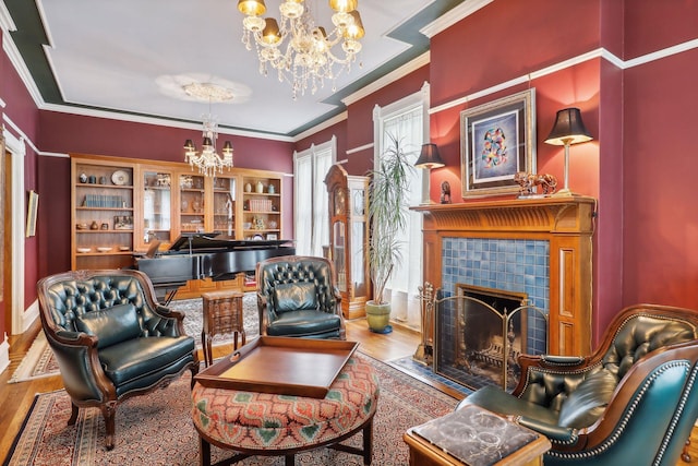 living area with hardwood / wood-style floors, a notable chandelier, ornamental molding, and a tiled fireplace