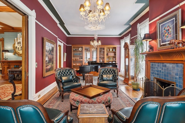 sitting room featuring hardwood / wood-style floors, a notable chandelier, crown molding, and a tile fireplace