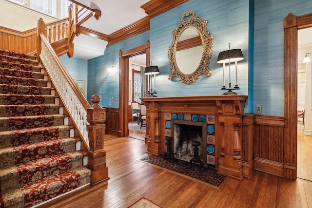 living room with a tiled fireplace, ornamental molding, and hardwood / wood-style flooring