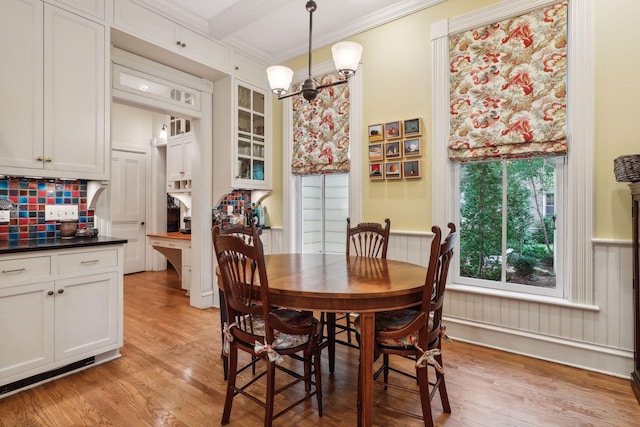 dining room with beam ceiling, crown molding, a chandelier, and light wood-type flooring