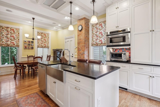 kitchen featuring a center island with sink, decorative light fixtures, and plenty of natural light