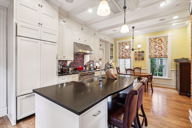 kitchen featuring white cabinetry, a kitchen island with sink, high quality appliances, and decorative light fixtures