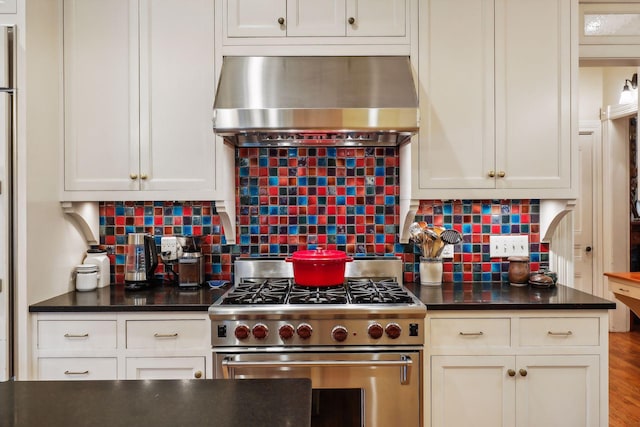 kitchen featuring decorative backsplash, wall chimney exhaust hood, stainless steel range, hardwood / wood-style floors, and white cabinetry