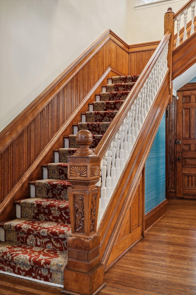 stairway with hardwood / wood-style floors and a towering ceiling