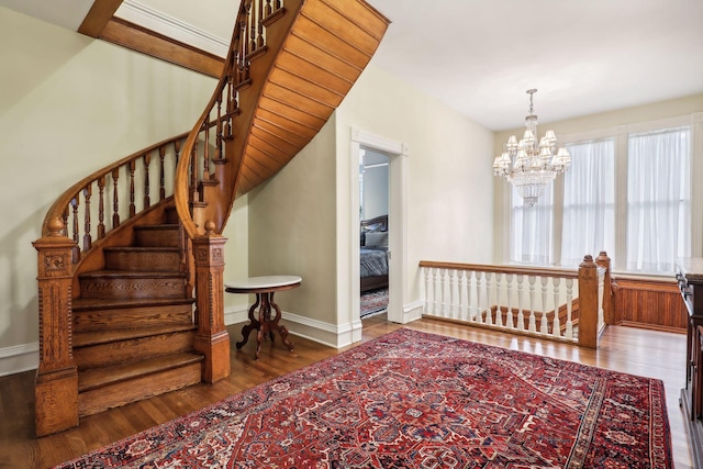 stairway with hardwood / wood-style floors and a notable chandelier