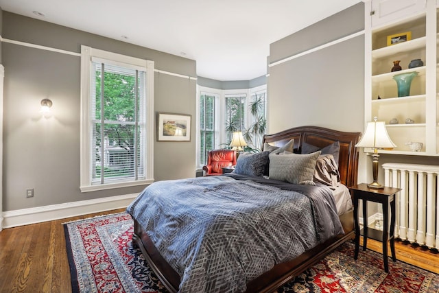 bedroom with radiator, dark hardwood / wood-style flooring, and multiple windows