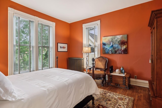 bedroom featuring multiple windows, dark hardwood / wood-style flooring, and radiator